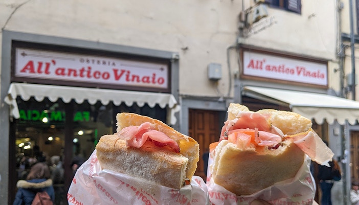 Visitors enjoying a Florence food tour with skip-the-line access at All’Antico Vinaio, sampling local delicacies.
