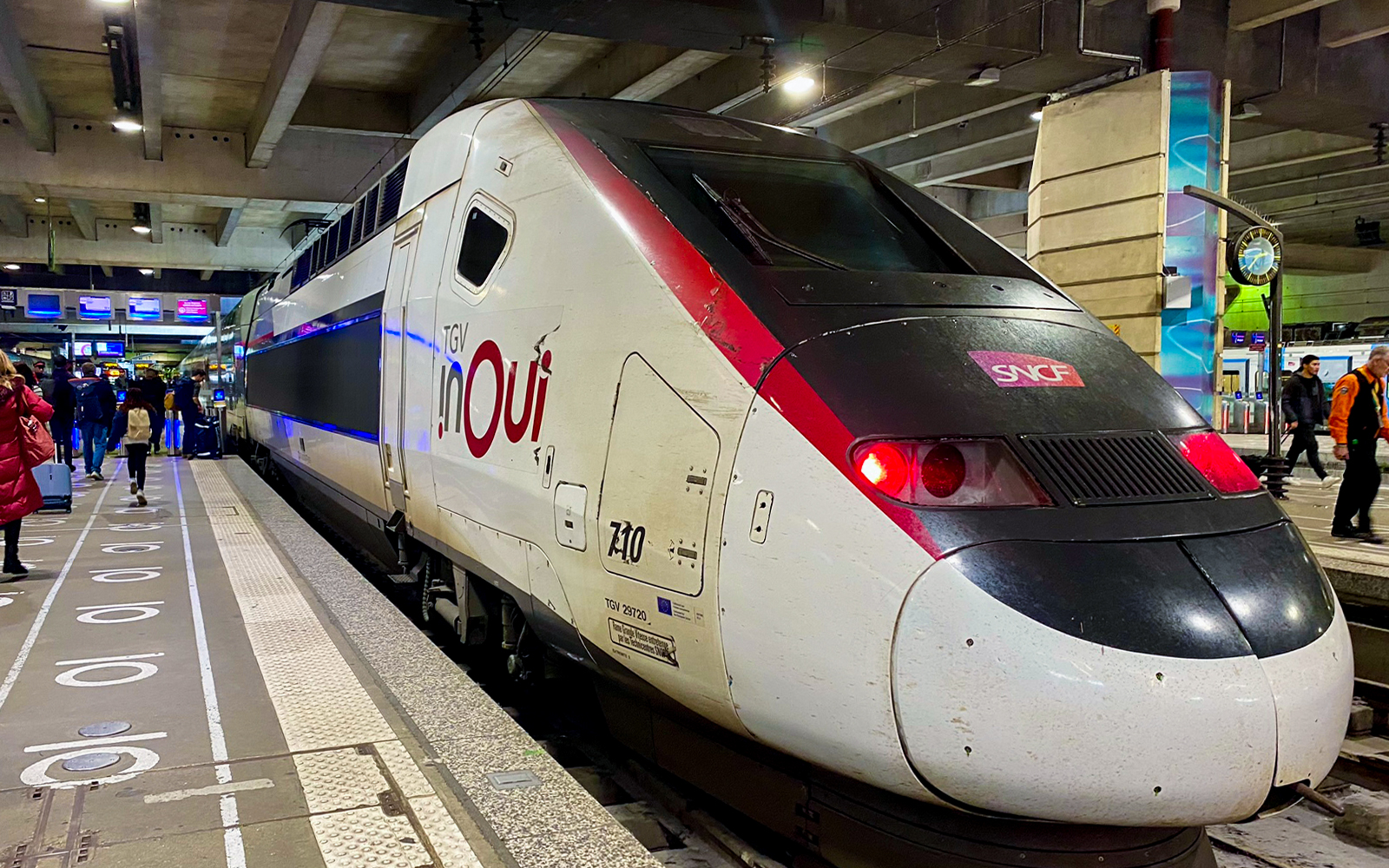 TGV train at a Paris station platform with passengers boarding.