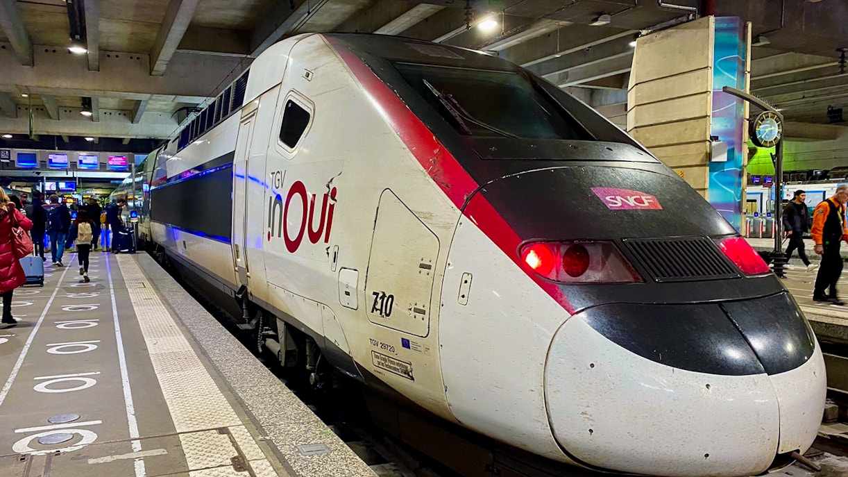 TGV train at a Paris station platform with passengers boarding.