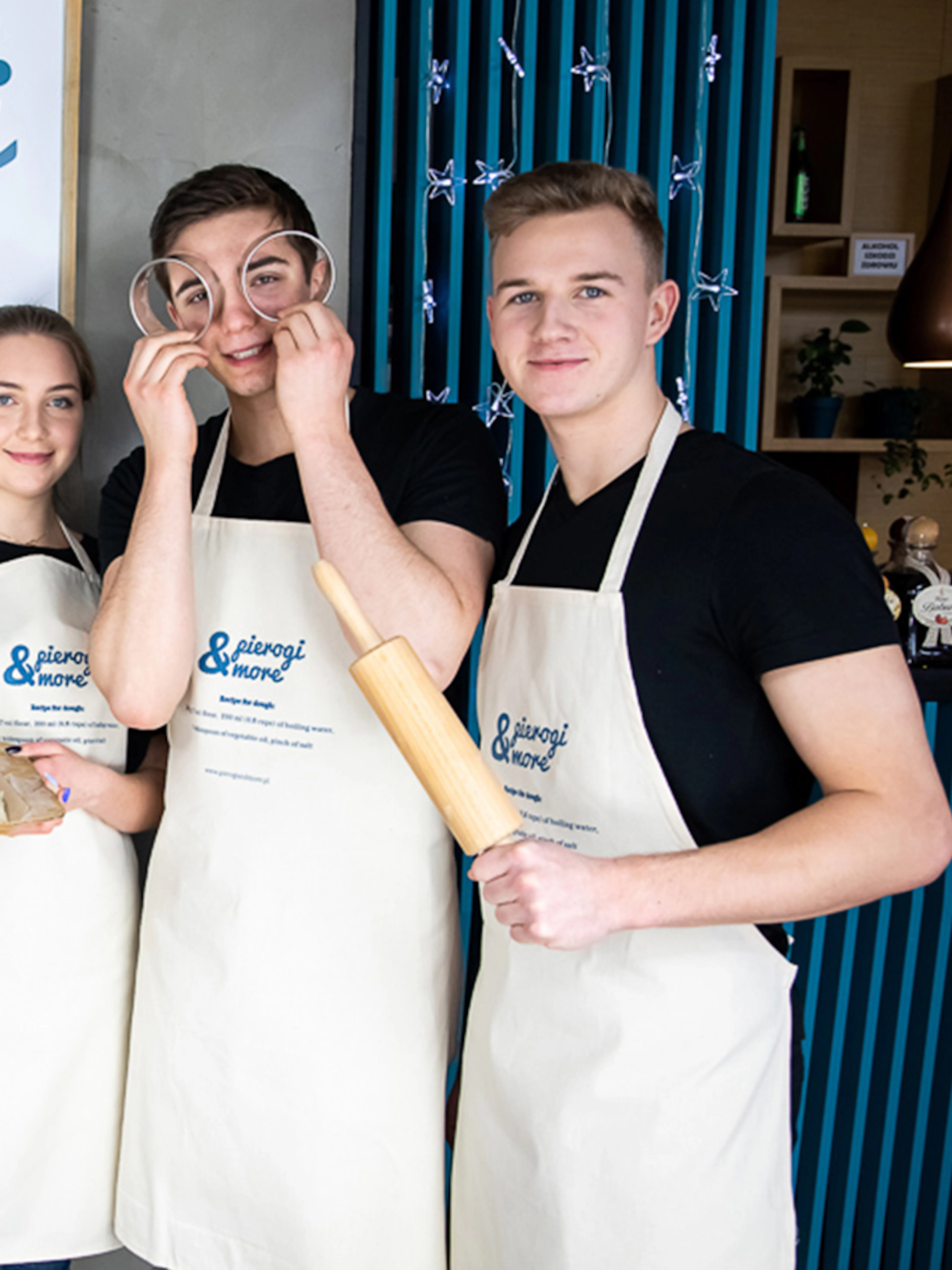 Group of people in aprons holding dumplings at a Polish cooking class.