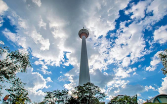 Kuala Lumpur Tower against a cloudy sky on the Putrajaya & Batu Caves Private Tour.