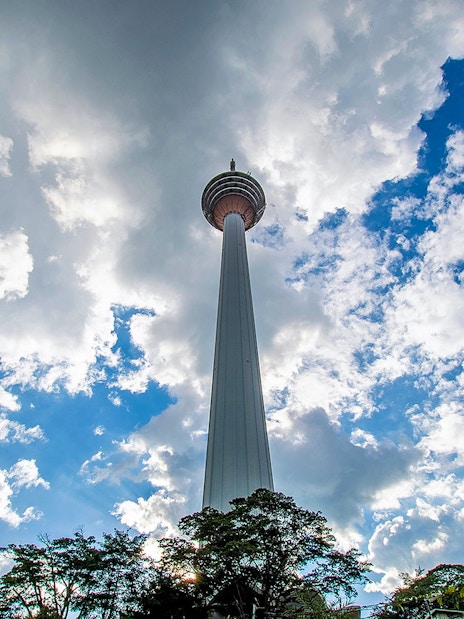 Kuala Lumpur Tower against a cloudy sky on the Putrajaya & Batu Caves Private Tour.