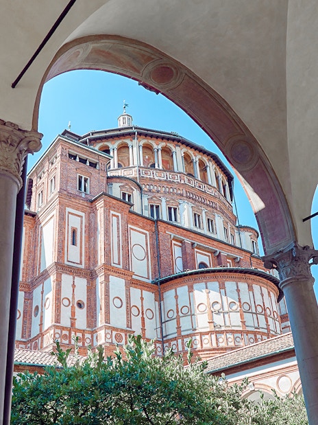 Santa Maria delle Grazie exterior, Milan, Italy, viewed through arches on a guided tour of Da Vinci's Last Supper.