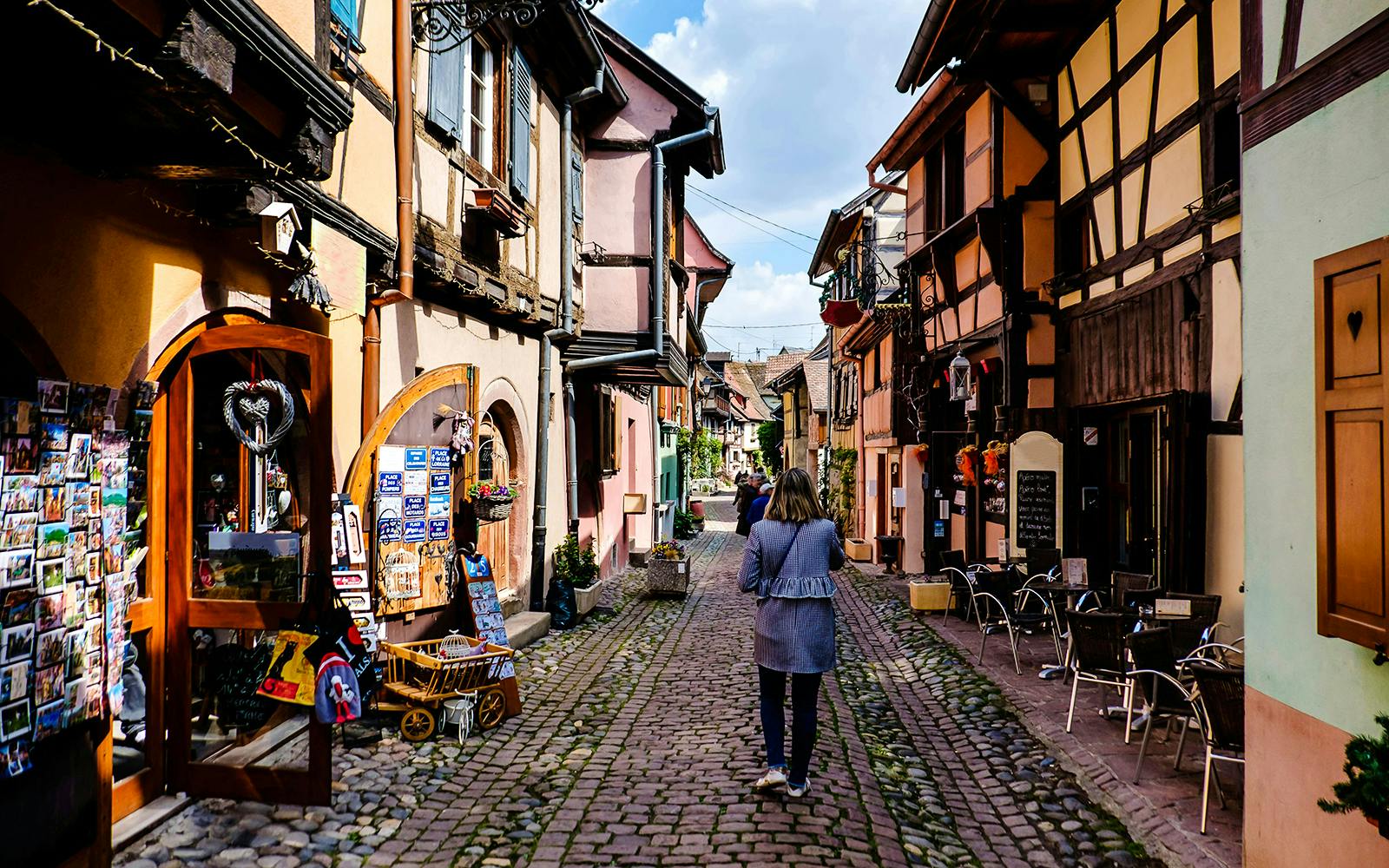 Cobblestone street with colorful half-timbered houses in Eguisheim, Alsace.