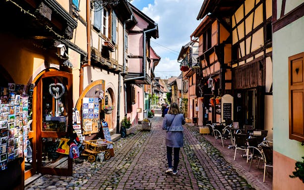 Cobblestone street with colorful half-timbered houses in Eguisheim, Alsace.
