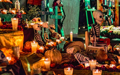 Day of the Dead altar with candles, marigolds, and skeleton figures in Mexico.