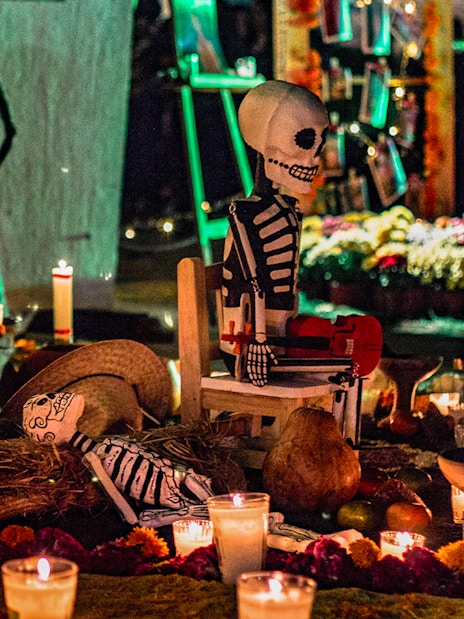 Day of the Dead altar with candles, marigolds, and skeleton figures in Mexico.