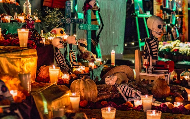 Day of the Dead altar with candles, marigolds, and skeleton figures in Mexico.