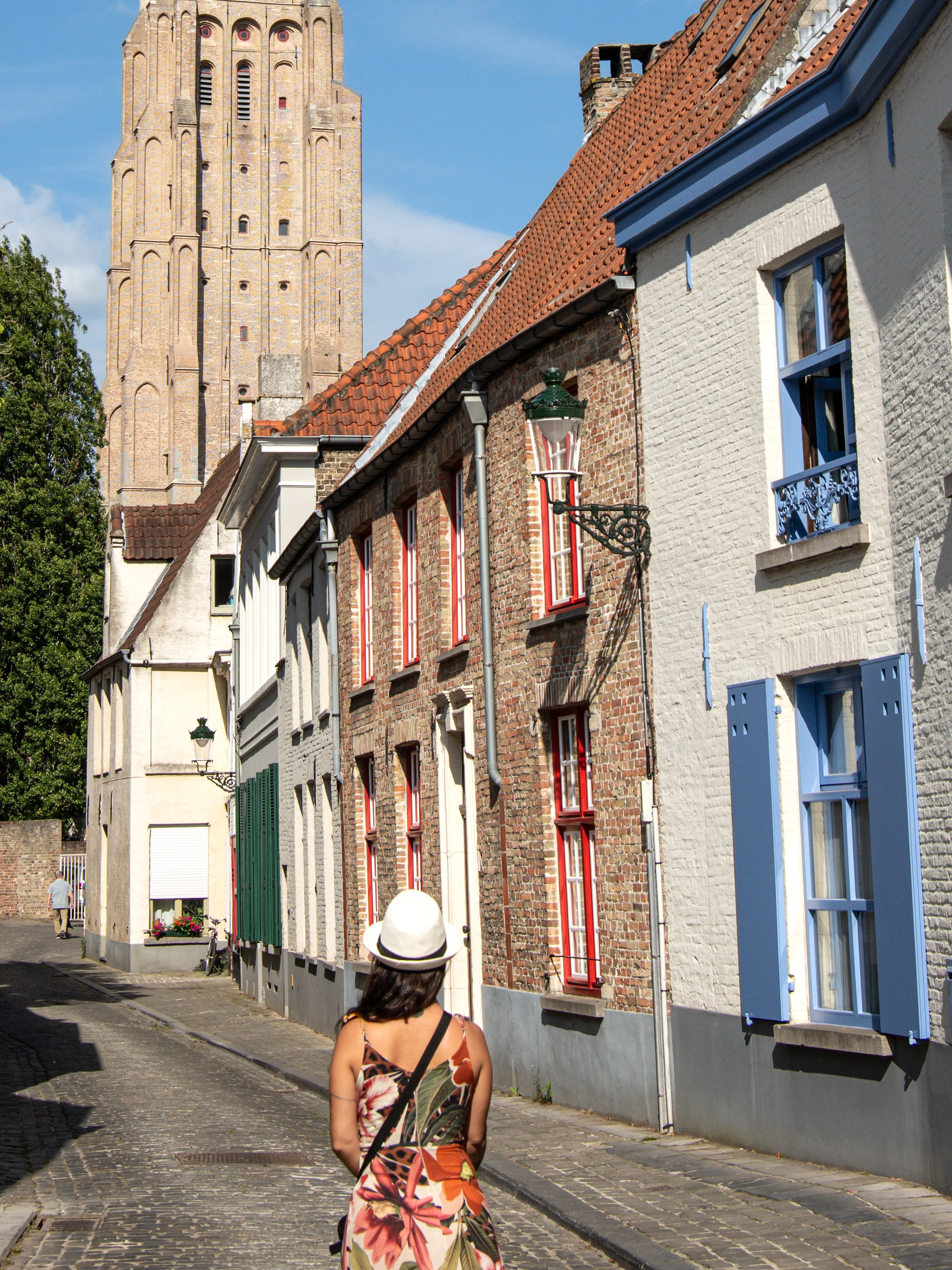 Woman walking on Stoofstraat toward Church of Our Lady, Bruges, Belgium.