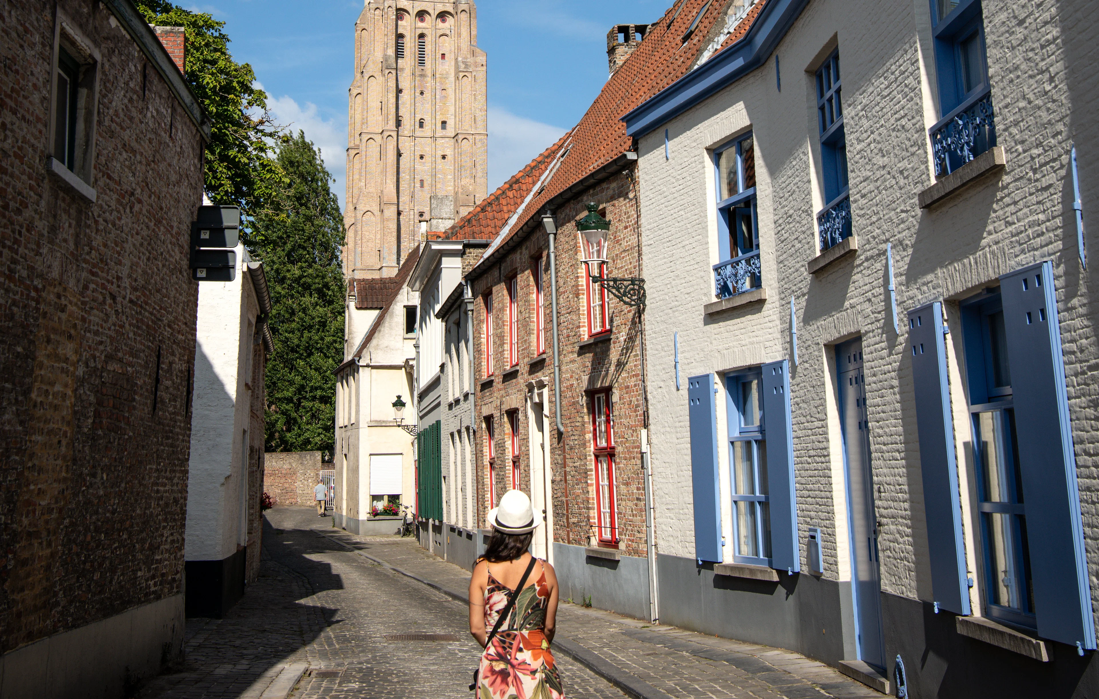 Woman walking on Stoofstraat toward Church of Our Lady, Bruges, Belgium.