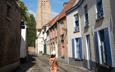 Woman walking on Stoofstraat toward Church of Our Lady, Bruges, Belgium.