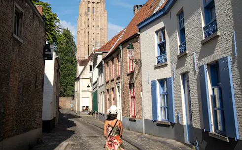 Woman walking on Stoofstraat toward Church of Our Lady, Bruges, Belgium.