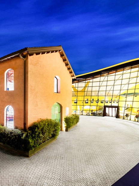 Museo Enzo Ferrari Modena entrance with modern glass facade at night.