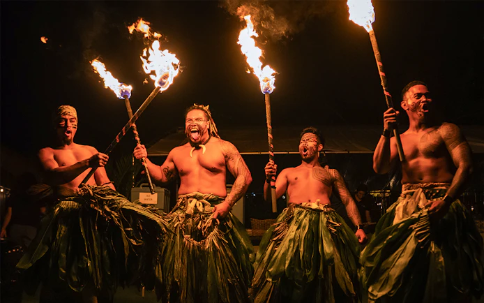 Fire dancers performing with torches on stage at Mauka Luau.