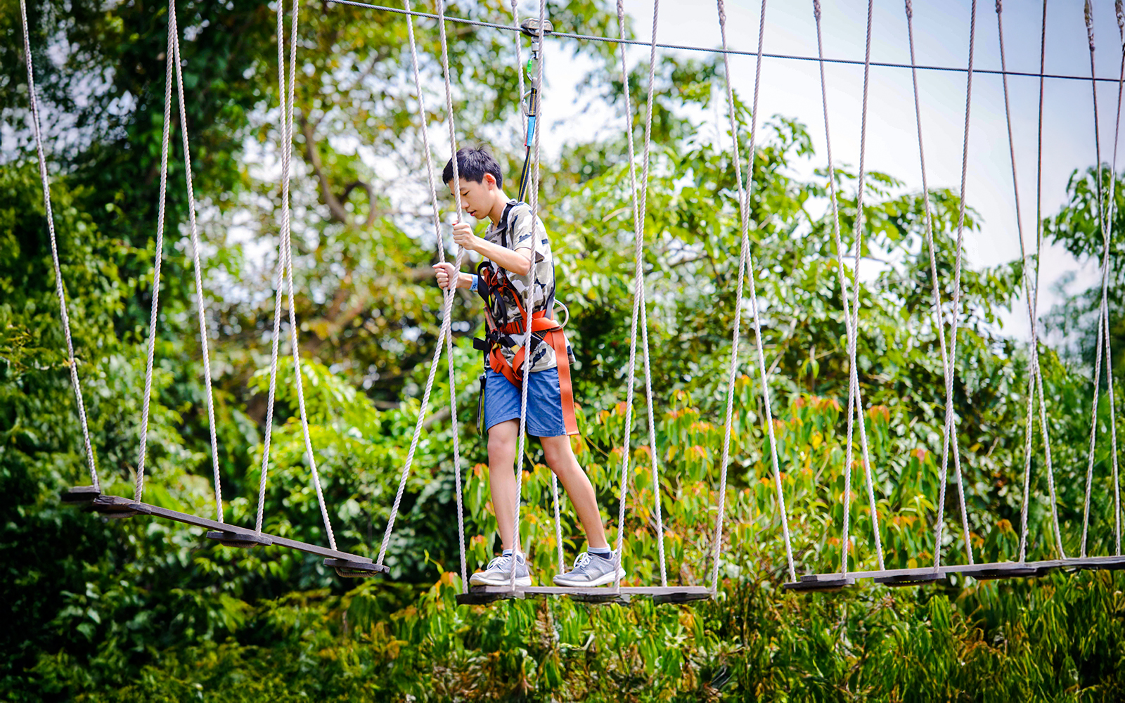 Participant crossing rope bridge at Mega Adventure Park Singapore.