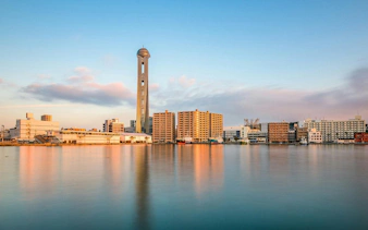 Shimonoseki waterfront skyline with Kaikyo Yume Tower and buildings reflecting on the water.