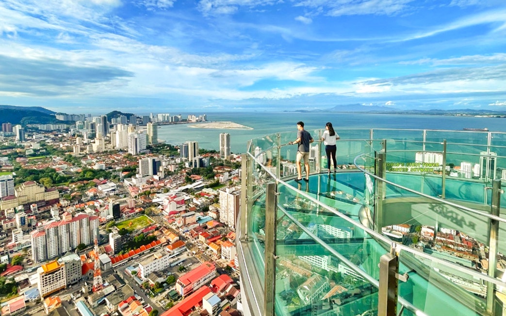 Couple enjoying the view from The Top, Penang's glass skywalk overlooking the city and sea.