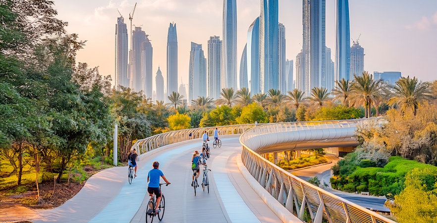 Cyclists on a winding track with Dubai skyline in the background.