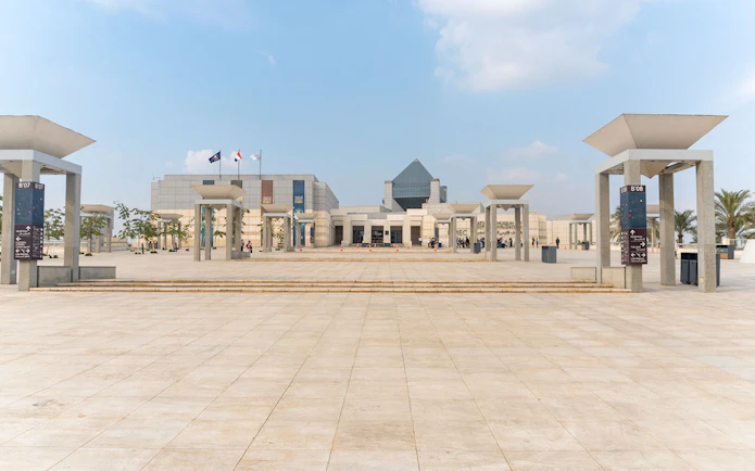 Entrance of the Museum of Civilization in Cairo with flags and modern architecture.