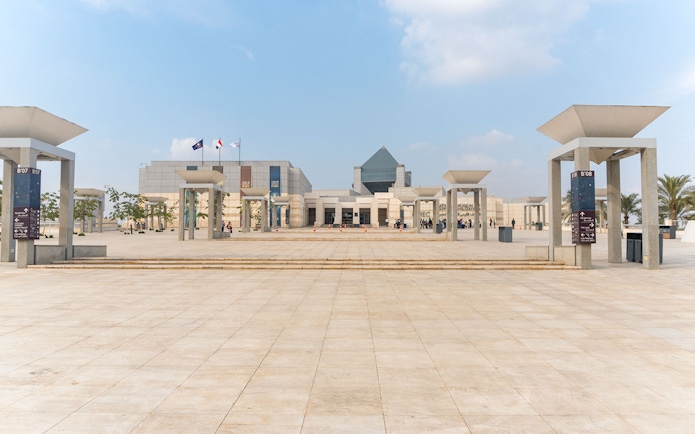 Entrance of the Museum of Civilization in Cairo with flags and modern architecture.
