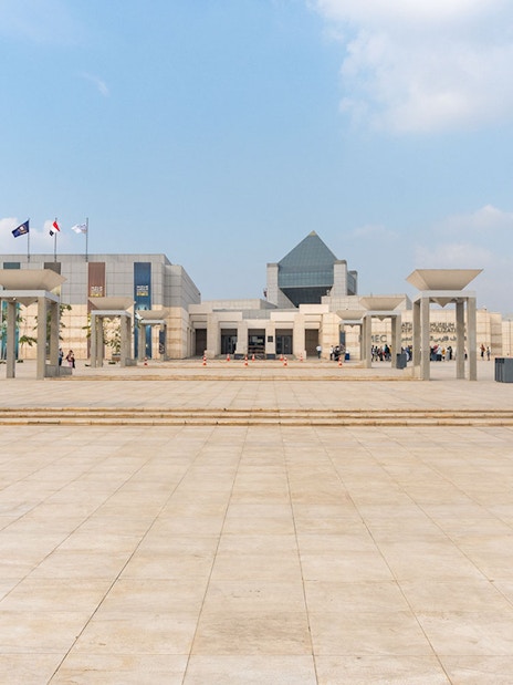 Entrance of the Museum of Civilization in Cairo with flags and modern architecture.