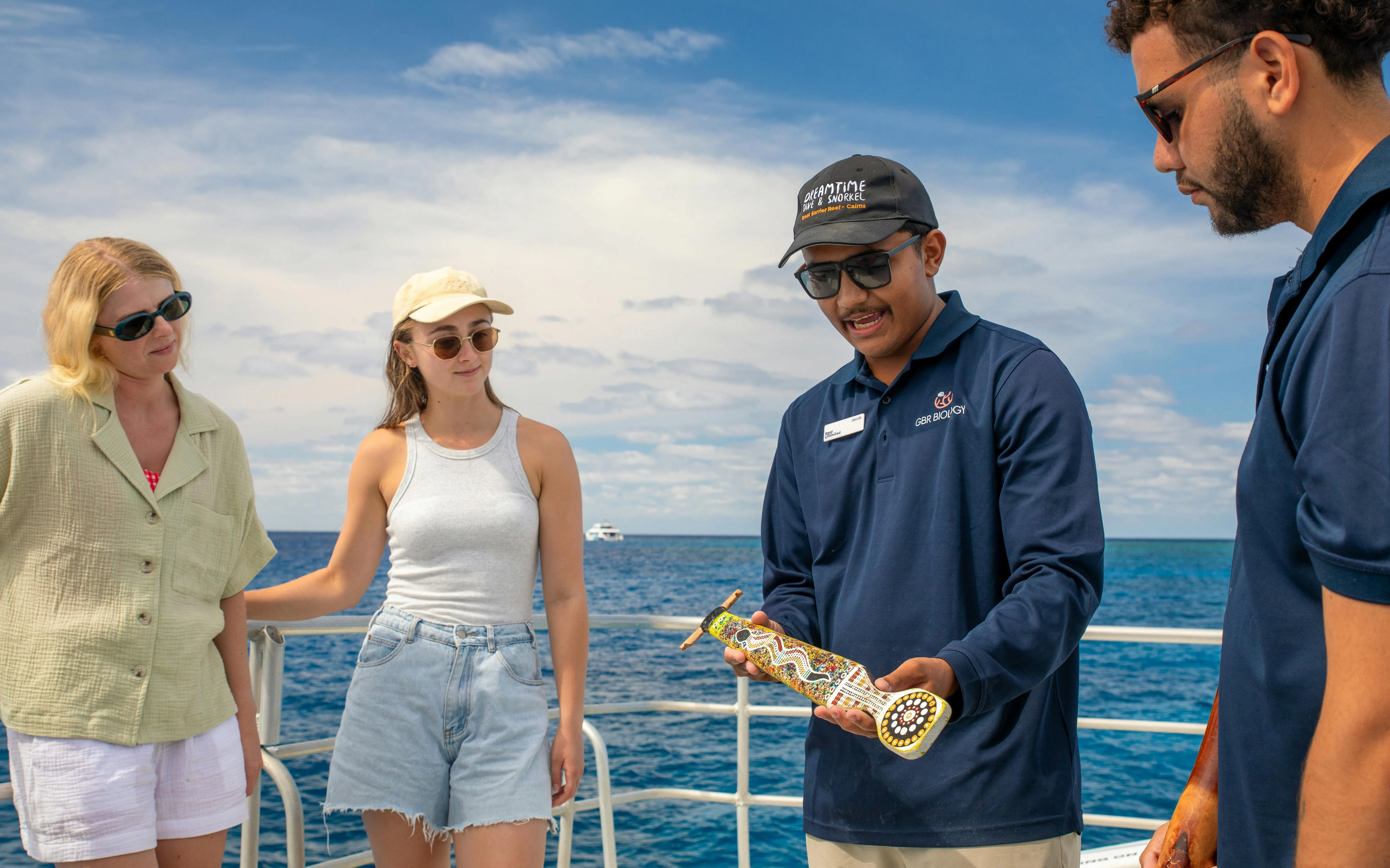Tour guide showing cultural artifact to tourists on a snorkel cruise from Cairns.