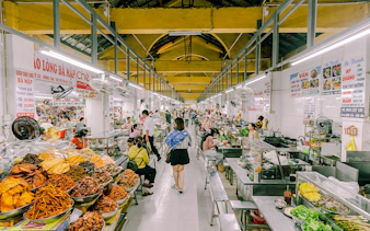 Da Nang market with food stalls and people enjoying breakfast during a guided city tour.