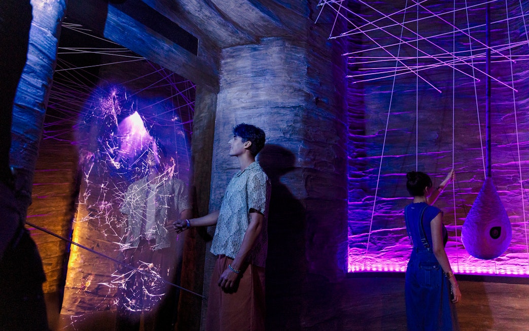 Visitors exploring cave spider exhibit at Exploria, Mandai Wildlife, with interactive web display.