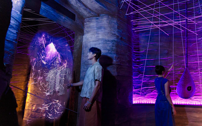 Visitors exploring cave spider exhibit at Exploria, Mandai Wildlife, with interactive web display.