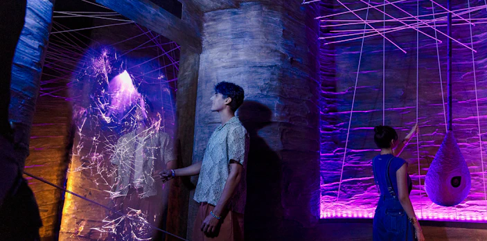Visitors exploring cave spider exhibit at Exploria, Mandai Wildlife, with interactive web display.
