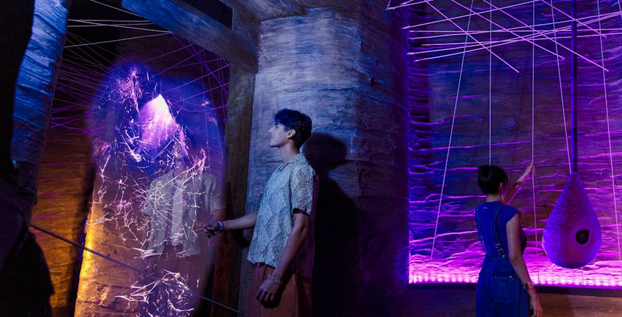 Visitors exploring cave spider exhibit at Exploria, Mandai Wildlife, with interactive web display.