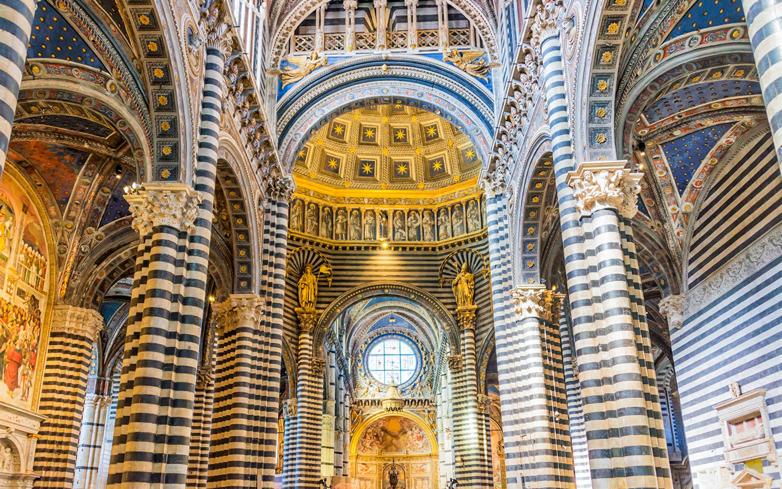 Siena Cathedral interior with striped columns and ornate ceiling.