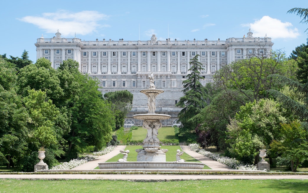 Royal Palace of Madrid exterior with fountain and gardens.