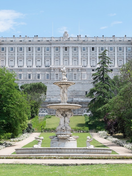Royal Palace of Madrid exterior with fountain and gardens.