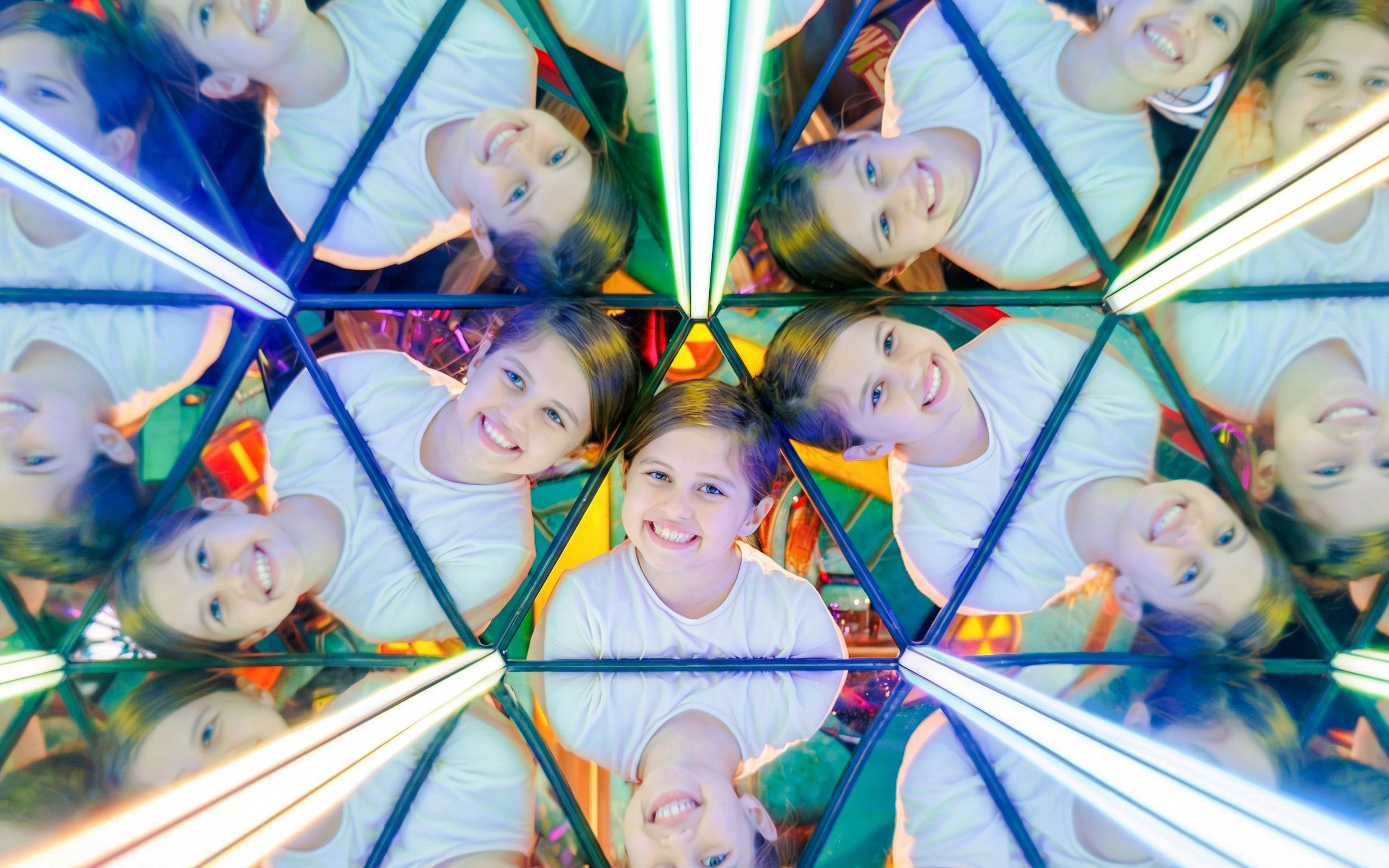Child smiling in a kaleidoscope mirror at TRICKD: Illusions, Fun, & More exhibit.