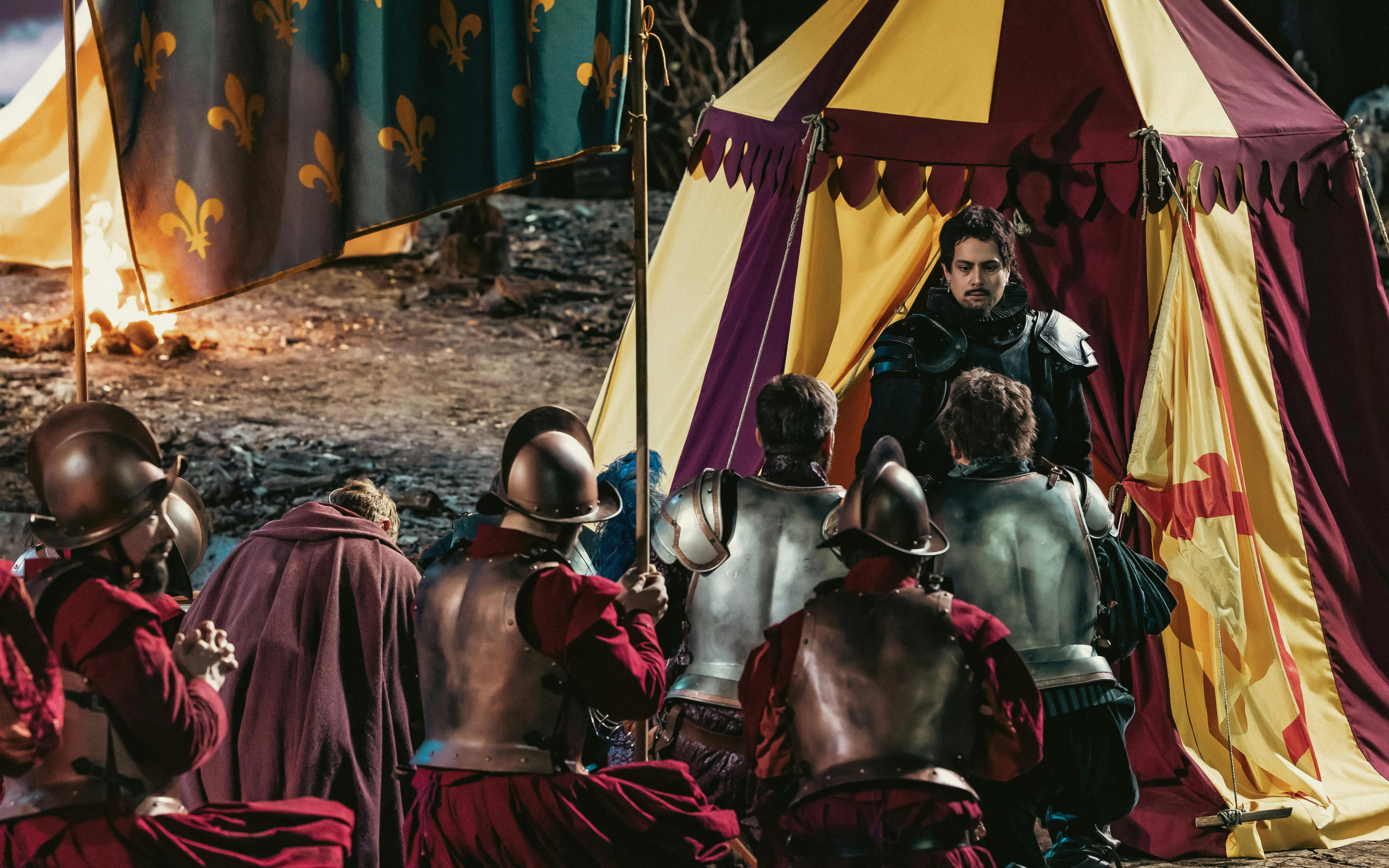 Knights kneeling before a tent with a man in armor, depicting a historical scene related to Willem van Oranje.