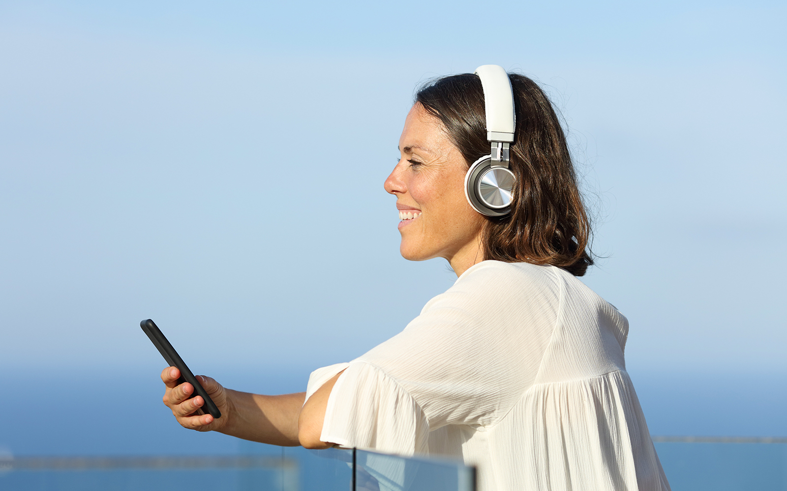 Person using a smartphone with headphones, enjoying a multilingual onboard guide.