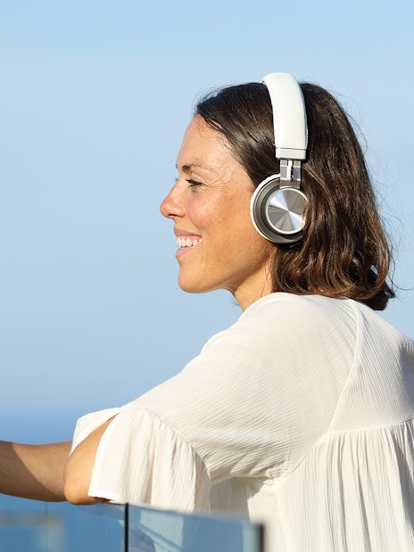 Person using a smartphone with headphones, enjoying a multilingual onboard guide.