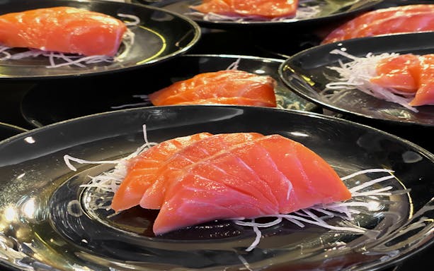 Sashimi served on black plates, part of the Bangkok Chao Phraya Princess Cruise dining experience.