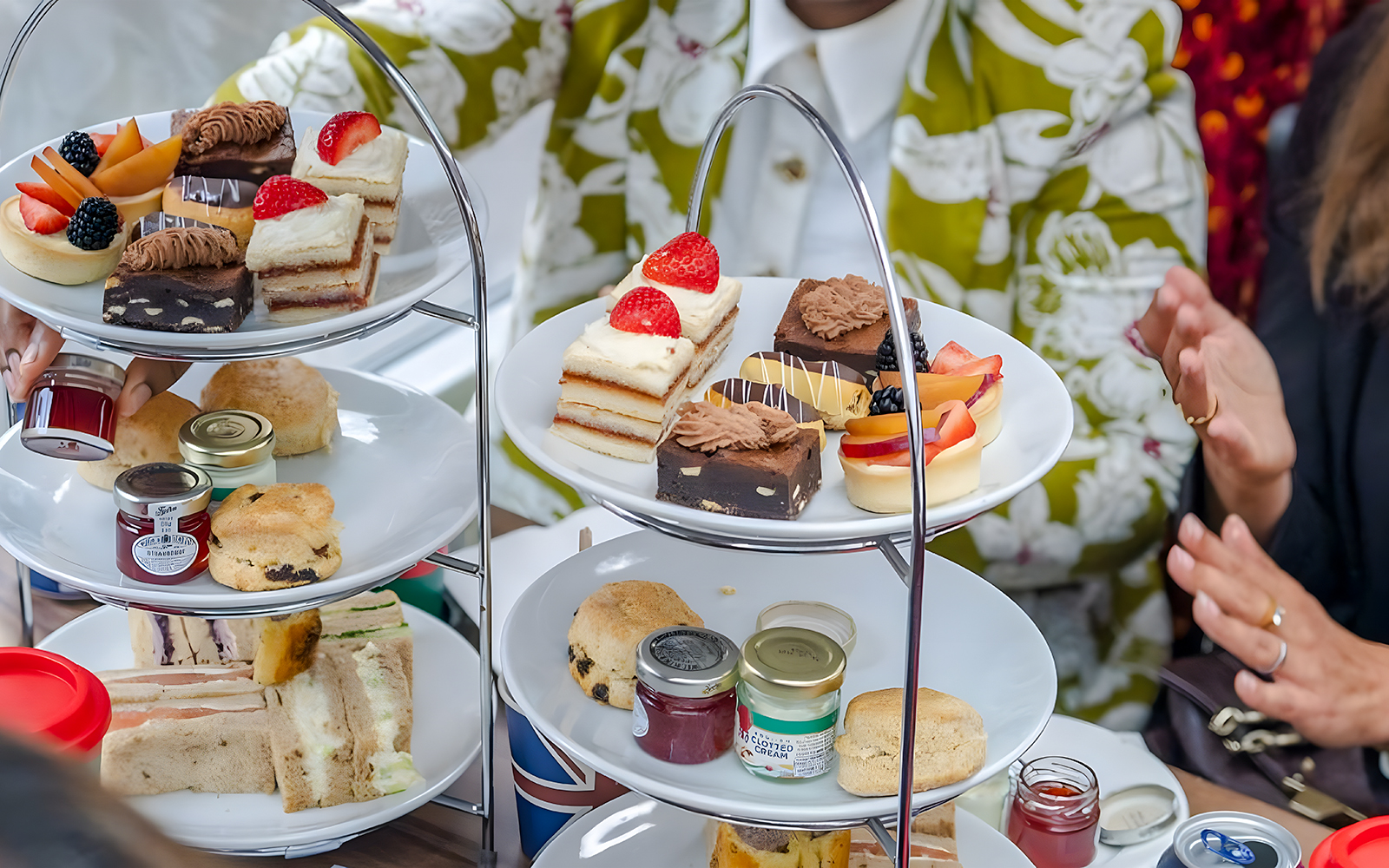 Afternoon tea pastries and sandwiches on a tiered stand during a London sightseeing bus tour.
