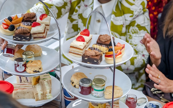 Afternoon tea pastries and sandwiches on a tiered stand during a London sightseeing bus tour.