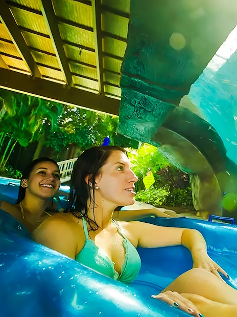 Two people on a lazy river ride at Aquatica Orlando, viewing underwater fish.