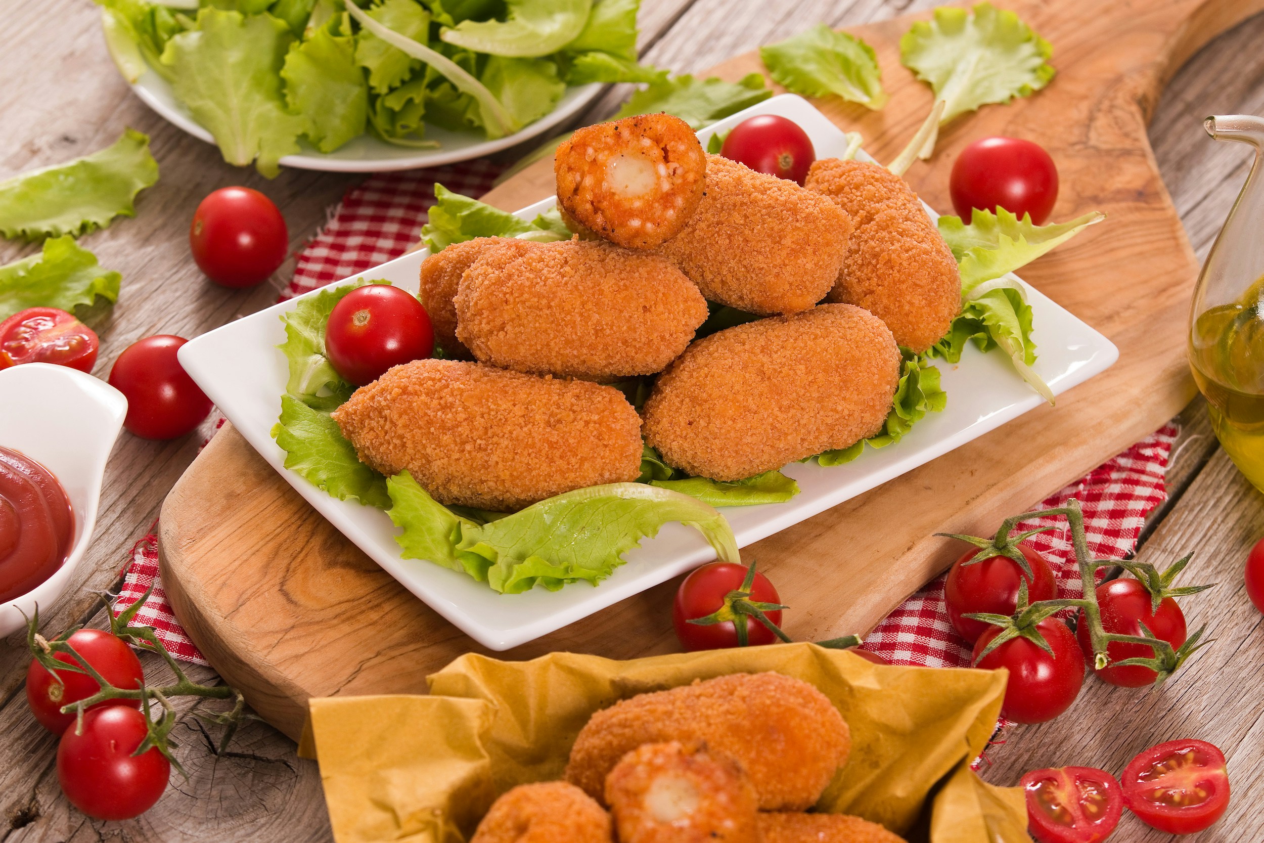 Suppli on a plate with lettuce and cherry tomatoes, Italian appetizer.
