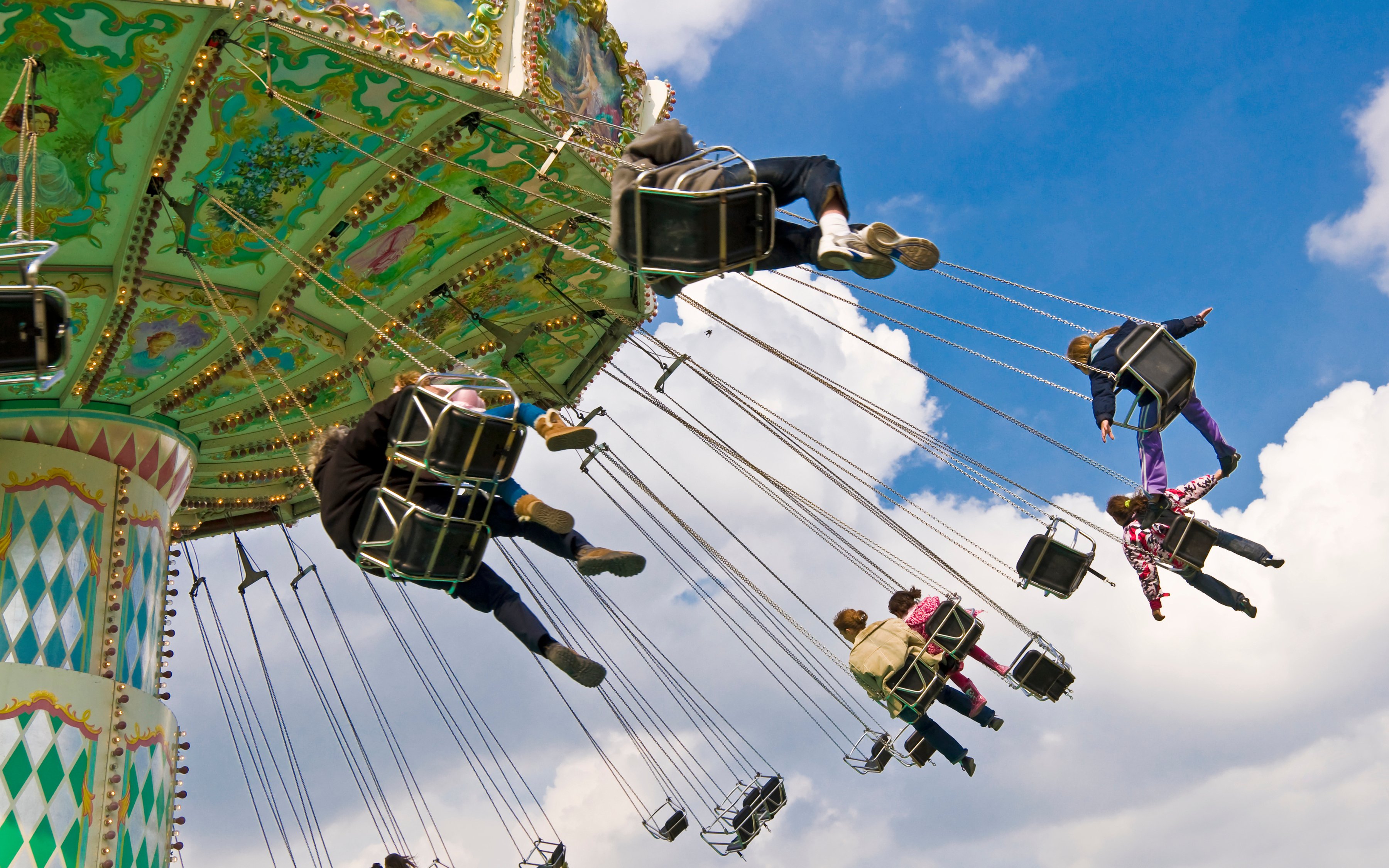 Carousel swing ride at Jardin d'Acclimatation, Paris, with people enjoying the attraction.