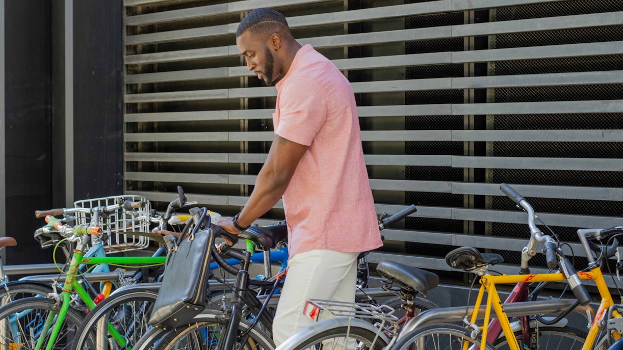 Man securing bicycle at urban bike rack.
