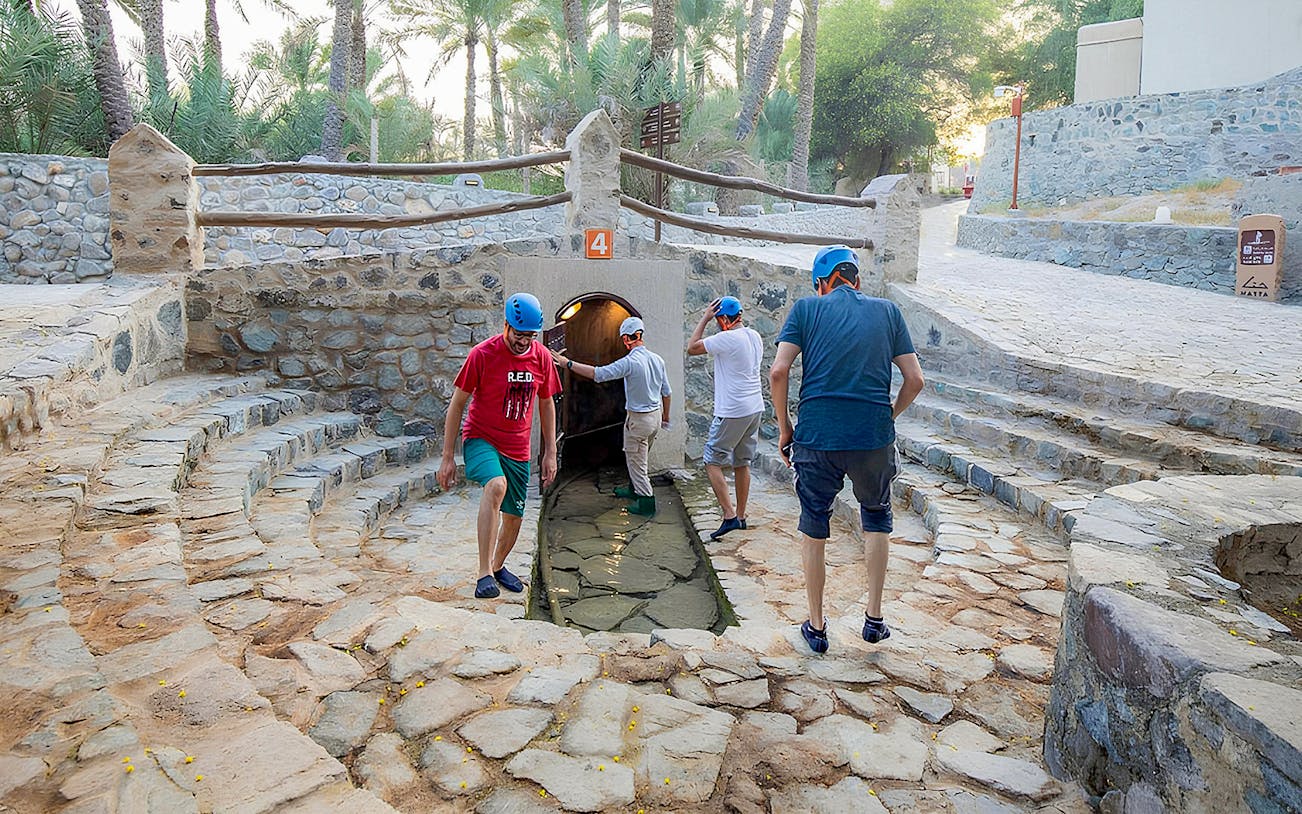 Visitors exploring Hatta Falaj water channel on a guided tour.