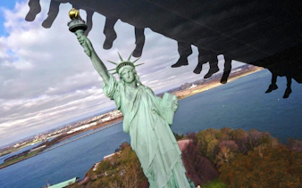 Guests on a ride at RiseNY with a view of the Statue of Liberty.