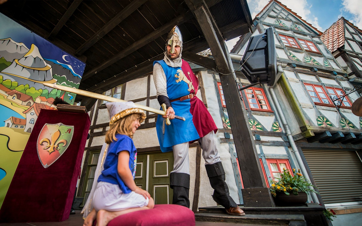 Knight performing at Belantis Adventure Park musical show with child on stage.