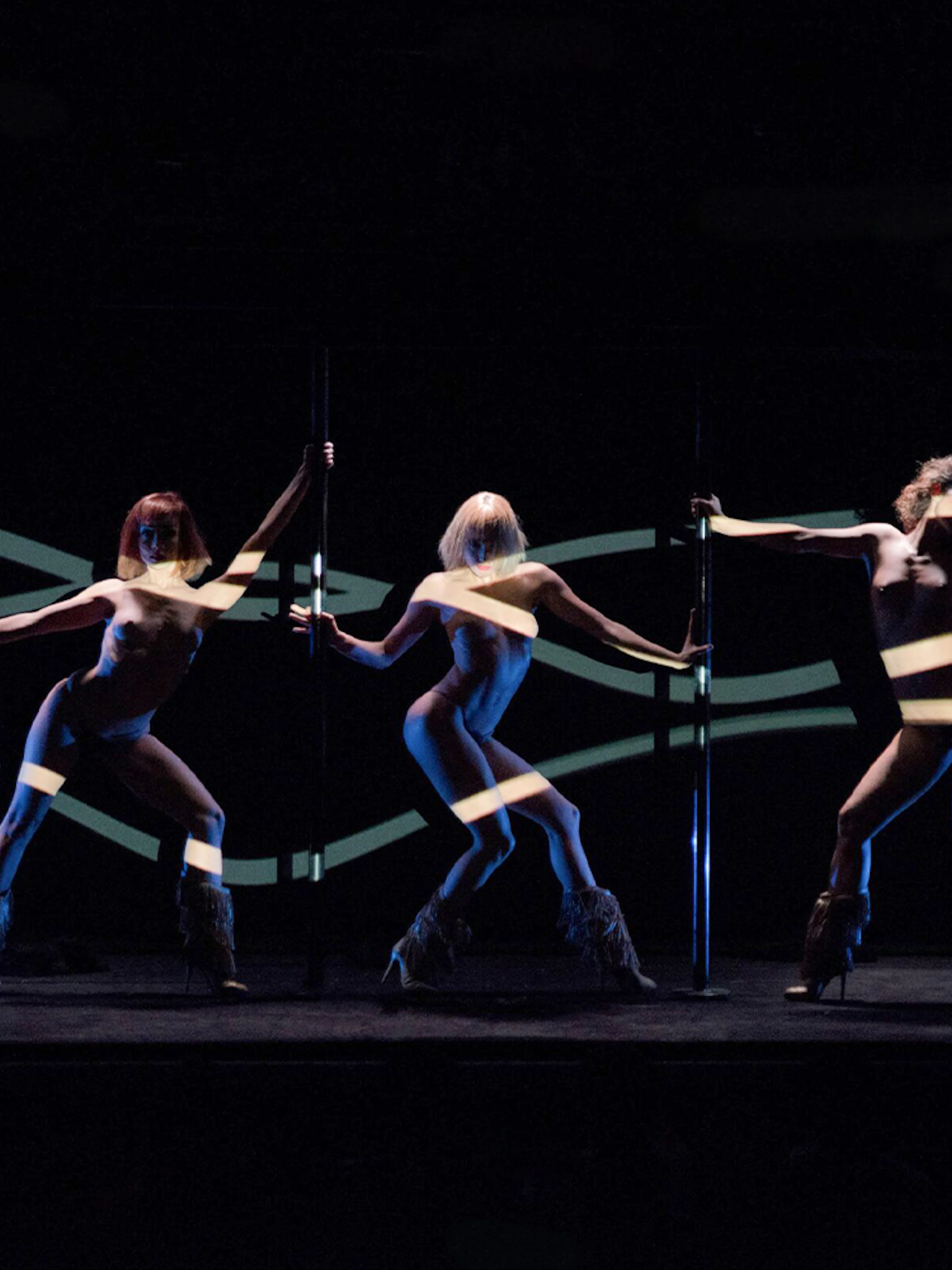 Dancers performing at Crazy Horse Paris show with dynamic lighting effects.