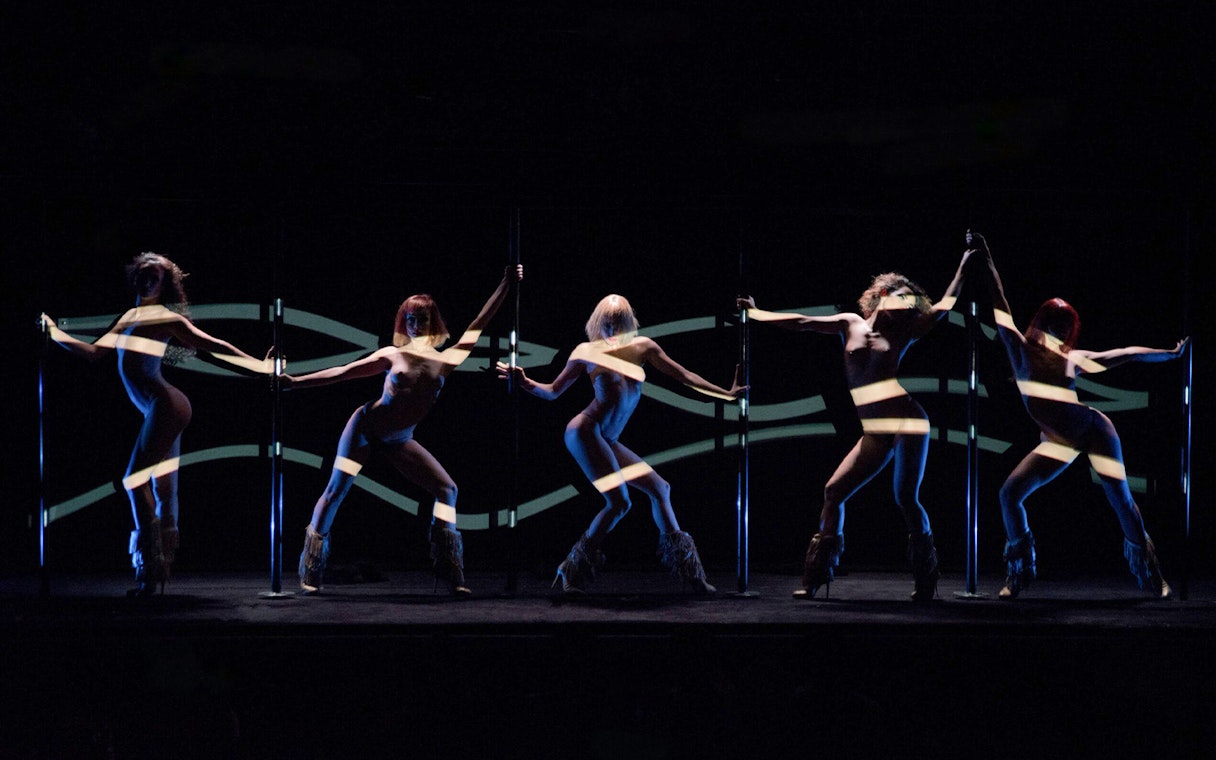 Dancers performing at Crazy Horse Paris show with dynamic lighting effects.